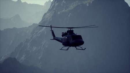 A helicopter hovers gracefully amidst towering mountains, illuminated by soft light from the setting sun. Natures beauty creates a stunning backdrop for aerial exploration.の写真素材