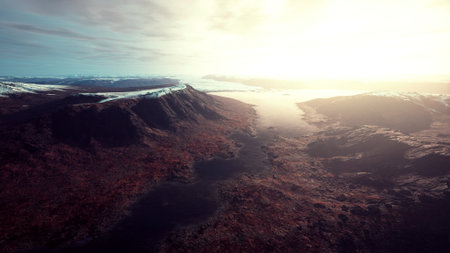 A breathtaking scene unfolds as the sun rises over distant mountains, casting golden light on a winding river below, while rocky terrains showcase natures raw beauty in the early morning.の写真素材