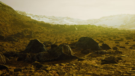 The scene showcases a rocky, barren landscape under a warm golden glow. Jagged rocks scatter across the ground, while distant hills and snow capped peaks hint at a majestic backdrop during twilight.の写真素材