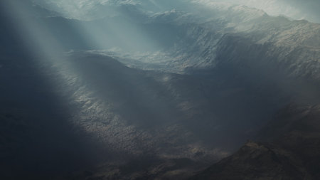 A serene view showcases a vast landscape filled with towering mountains and deep valleys. Gentle beams of sunlight pierce through clouds, illuminating the rugged terrain beautifully.の写真素材