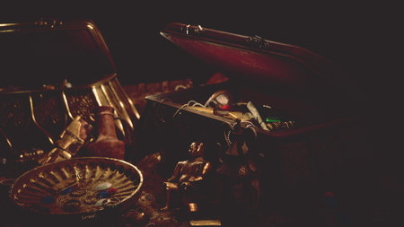A treasure chest filled with gold items and ancient artifacts sits in a dark room. The soft light casts shadows on the ornate artifacts, creating an atmosphere of mystery and discovery.の写真素材