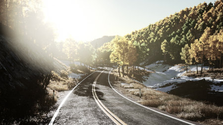 A winding road curves through a picturesque landscape, surrounded by golden trees. Early morning...