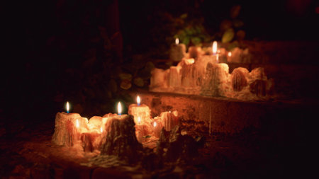 Candlelight softly glows along a stone pathway, casting gentle shadows among the greenery. This tranquil scene creates a peaceful ambiance during a quiet night.の写真素材