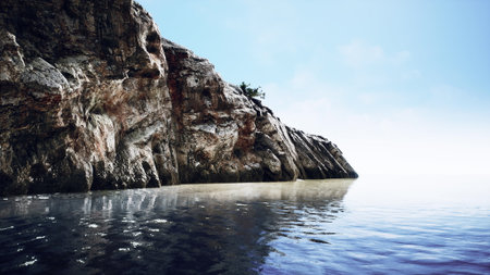 Waves gently lap against towering cliffs that rise majestically by the shore. Under clear blue skies, the tranquil water reflects the stunning landscape, inviting peace and exploration.の写真素材