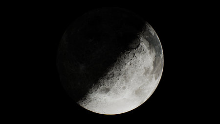 A stunning crescent moon shines brightly in the night sky, casting gentle light. The surface...