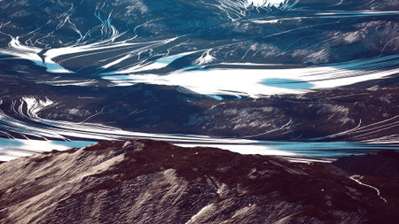 Winding rivers and glaciers create fascinating patterns across the rugged landscape, showcasing...