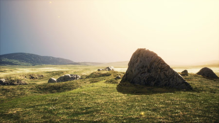 In a serene landscape, golden sunlight illuminates the rolling hills and scattered rocks.の写真素材
