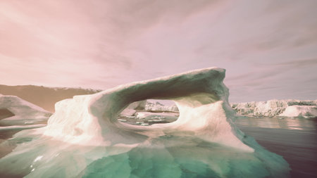 A breathtaking ice arch juts out from the icy waters, surrounded by floating icebergs. The warm hues of sunset reflect on the surface, creating a magical atmosphere in the Arctic.の写真素材
