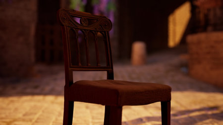 A solitary wooden chair stands in a peaceful alley, bathed in warm sunlight during the evening. Shadows play along the cobblestone path, creating a serene atmosphere.の写真素材