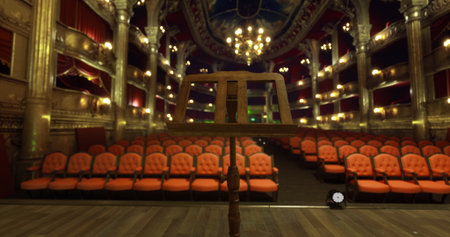 A classic theater is set for a performance, showcasing an empty stage with a music stand. Richly decorated, the venue features red seats and ornate details, creating an inviting atmosphere.の写真素材
