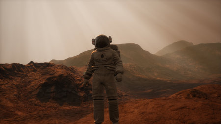 An astronaut stands on the dusty surface of Mars amidst rocky formations, bathed in soft, diffused sunlight. The vast Martian landscape stretches endlessly into the horizon.の写真素材