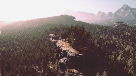 Morning light bathes a serene mountainous landscape, highlighting green forests and rocky cliffs. The tranquil scene invites exploration and appreciation of natures beauty.の写真素材