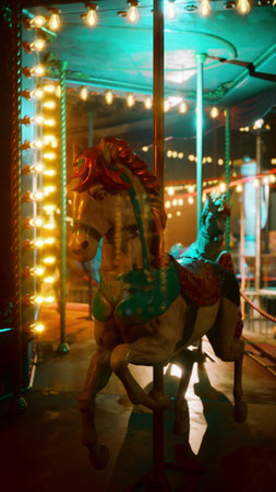 Colorful carousel horses stand still under glowing lights, showcasing their vintage charm. The scene captures a serene night ambience, hinting at joyful memories of laughter and fun.の写真素材