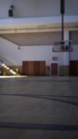 A spacious basketball court awaits players in the afternoon light. Shadows stretch across the polished floor as excitement builds for the upcoming practice session.の写真素材