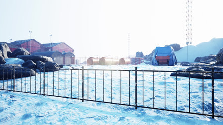 A stunning white landscape showcases rocks and ice around a research station. Bright sunlight illuminates the scene, highlighting the solitude and beauty of this remote location.の写真素材