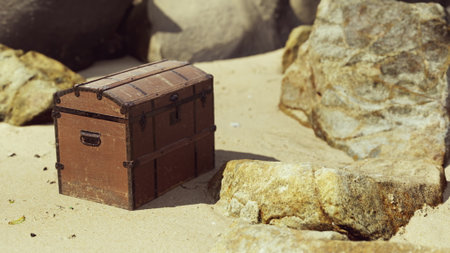 A wooden treasure chest sits on a sunlit sandy beach, framed by smooth rocks. The scene captures a moment of calmness and adventure, inviting curiosity and exploration.の写真素材