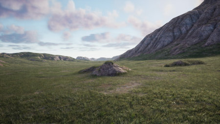 A peaceful scene unfolds as the sun sets behind rolling hills. Rocky formations rise above vibrant green grass, casting long shadows in the soft light. Natures calm beauty is on display.の写真素材