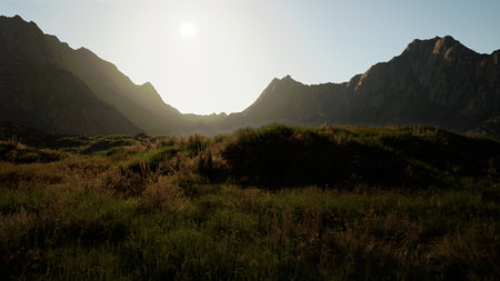 Rolling hills and towering peaks greet the dawn light, casting a warm glow over lush grass. Nature awakens in breathtaking beauty, inviting exploration in the serene landscape.の写真素材