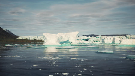 Majestic icebergs float quietly in calm Arctic waters under a cloud dotted sky. The breathtaking...