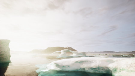 A stunning view captures the tranquil Arctic waters at sunrise, showcasing majestic ice formations and distant mountains under a soft, glowing sky. The scene evokes peace and natural beauty.の写真素材