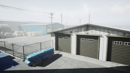 A tranquil scene of an industrial storage area featuring several garage units and stacks of materials. The setting is misty, creating a serene and calm atmosphere under the soft light.の写真素材