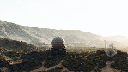 A striking observation dome stands alone amidst a vast desert terrain. Surrounding rocky formations and low shrubs create a serene atmosphere as the sun sets, casting long shadows.の写真素材