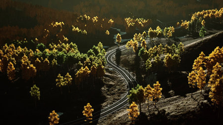 Golden leaves light up the landscape as a winding road meanders through a serene forest. The setting sun casts a warm glow, making the scenery truly enchanting.の写真素材