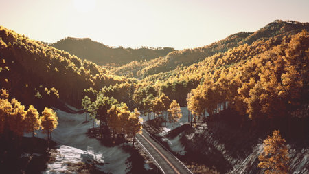 A beautiful view of rolling mountains covered with golden and green trees during autumn. A train track winds through the valley, capturing the essence of nature and tranquility.の写真素材