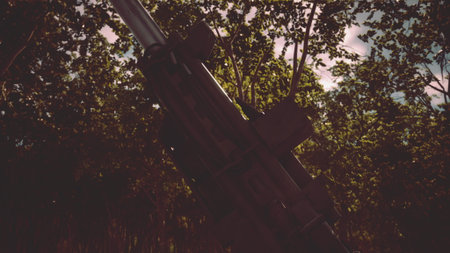 Metal glimmers as the gun barrel stands amidst tall trees and vibrant leaves. Sunlight filters through the canopy, creating an intriguing contrast in this untamed landscape.の写真素材