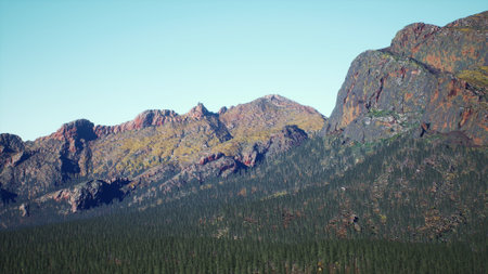 Majestic mountains rise dramatically against a clear blue sky. Lush green forests blanket the foothills, creating a serene atmosphere. A perfect day for exploring the great outdoors.の写真素材