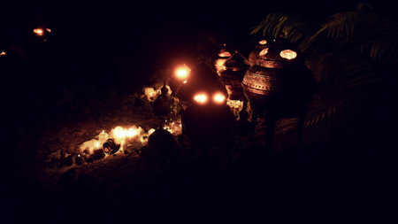 At night, warm lanterns illuminate traditional pottery on a quiet beach. The soft light creates a peaceful atmosphere, surrounded by gentle waves and a starry sky.の写真素材