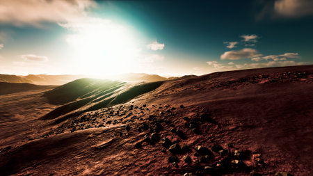 A breathtaking view of a Martian landscape during dusk shows rolling hills and scattered rocks illuminated by a warm, glowing sun. The sky features soft clouds and vibrant hues.の写真素材