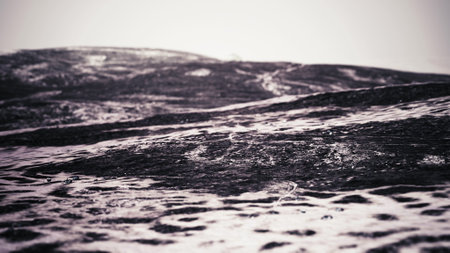 Rippling water moves over textured surfaces as soft light filters down, creating a serene atmosphere by the shoreline. The scene evokes a sense of calm and tranquility, inviting contemplation.の写真素材