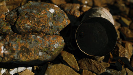 A weathered metal cup lies on a bed of vibrant stones beside a calm lake. The scene captures the beauty of nature, blending rustic artifacts with colorful textures and peaceful surroundings.の写真素材