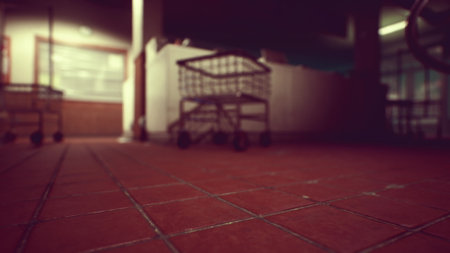 Empty shopping carts stand in a dimly lit grocery store. The warm glow from overhead lights adds a cozy ambiance to the serene atmosphere, creating a sense of calm.の写真素材