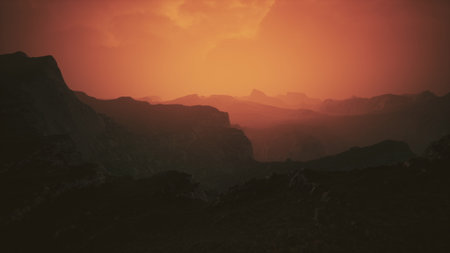 A stunning sunset illuminates the rugged contours of distant mountains, blending oranges and reds in the sky. This tranquil moment showcases natures beauty, inviting serenity and reflection.の写真素材