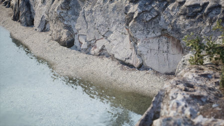 Nestled between towering cliffs, a tranquil lake reflects the bright blue sky. The sandy shoreline stretches across the waters edge, inviting exploration and peace amid natures beauty.の写真素材