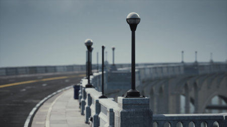 A serene road winds alongside a bridge, accentuated by stylish lamp posts that stand tall against the backdrop of a moody sky. The scene captures a tranquil moment in an urban setting.の写真素材
