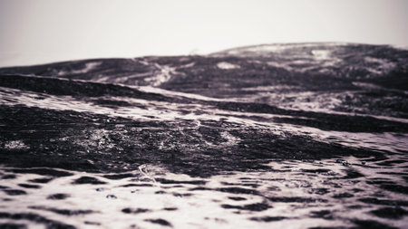 Soft, dark waves curl and flow across an expansive surface, creating a serene and calm atmosphere. The horizon stretches endlessly, instilling a sense of quiet contemplation.の写真素材