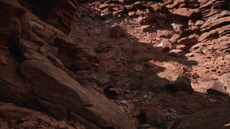 A rugged terrain of red rocks and pebbles spreads across the ground, illuminated by sunlight....