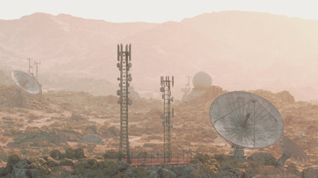 Tall communication towers and large satellite dishes stand against a stunning sunset in a remote desert area. The landscape features rocky terrain and a warm golden glow.の写真素材
