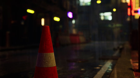 A vibrant city street soaked in rain showcases colorful neon lights. A solitary traffic cone stands beside the wet pavement, reflecting the bustling life around it during a rainy night.の写真素材