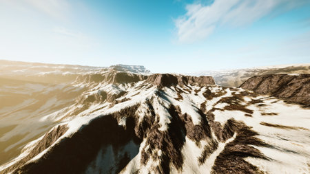 Rolling hills of rugged mountains stretch into the distance, covered in patches of snow. The warm glow of sunlight highlights the natural beauty and texture of the landscape.の写真素材