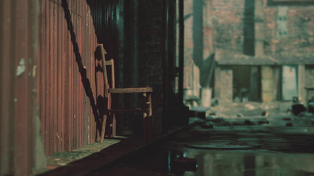 A weathered wooden chair rests against a rusted wall in a deserted alley. Sunlight filters through, illuminating scattered debris and creating a sense of stillness and solitude.の写真素材
