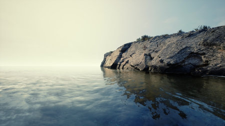 Soft morning light caresses a tranquil shoreline, where smooth waters meet rugged rocks. The peaceful scene invites quiet reflection and natural beauty.の写真素材