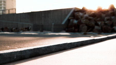 In the vibrant city, the warm glow of the setting sun casts a serene light on the textured pavement. Nearby, rugged stones lay peacefully, adding character to the urban environment.の写真素材