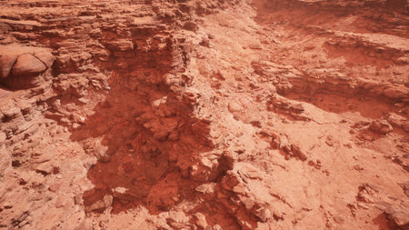 Dusty red formations stretch across the horizon, showcasing rugged cliffs and deep gorges bathed in warm light during the golden hour.の写真素材