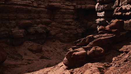 A dramatic canyon landscape features striking red rocks and towering walls under bright sunlight. Shadows enhance the textures and colors of the geological formations, creating an awe inspiring sight.の写真素材