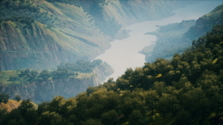 Witness a breathtaking view of a tranquil river coursing through verdant hills. The landscape is alive with rich foliage and distant peaks, creating a peaceful atmosphere.の写真素材