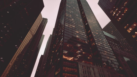 Skyscrapers rise dramatically against a twilight sky, their glass facades reflecting warm light. The urban scene captures the energy and vibrancy of a lively metropolis.の写真素材